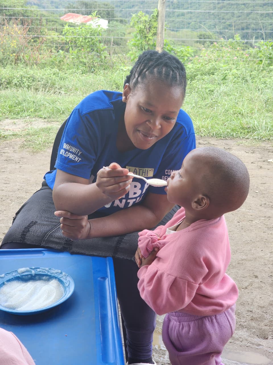 A teacher feeding a child at breakfast