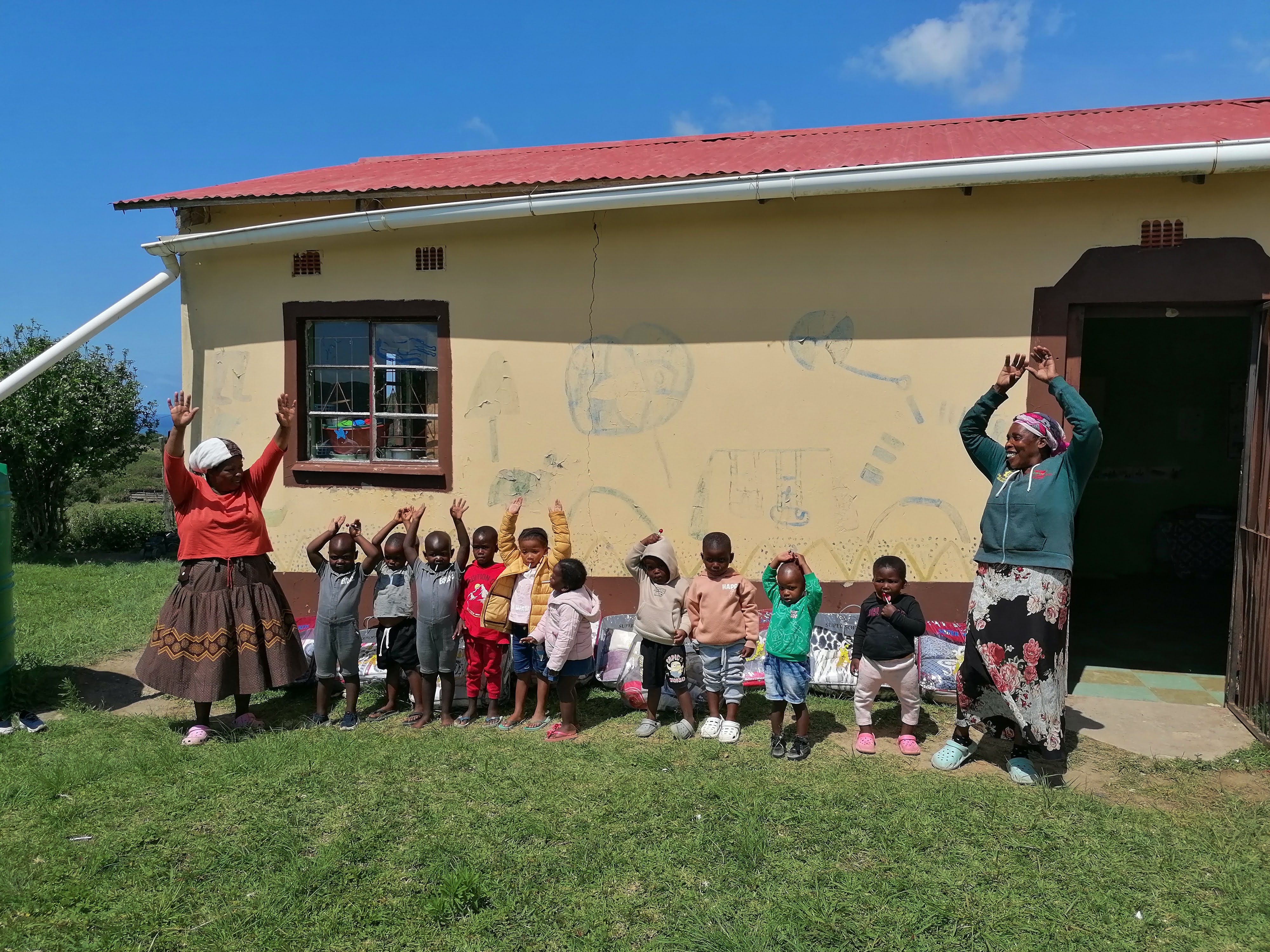 Children and caregivers together outside a community building