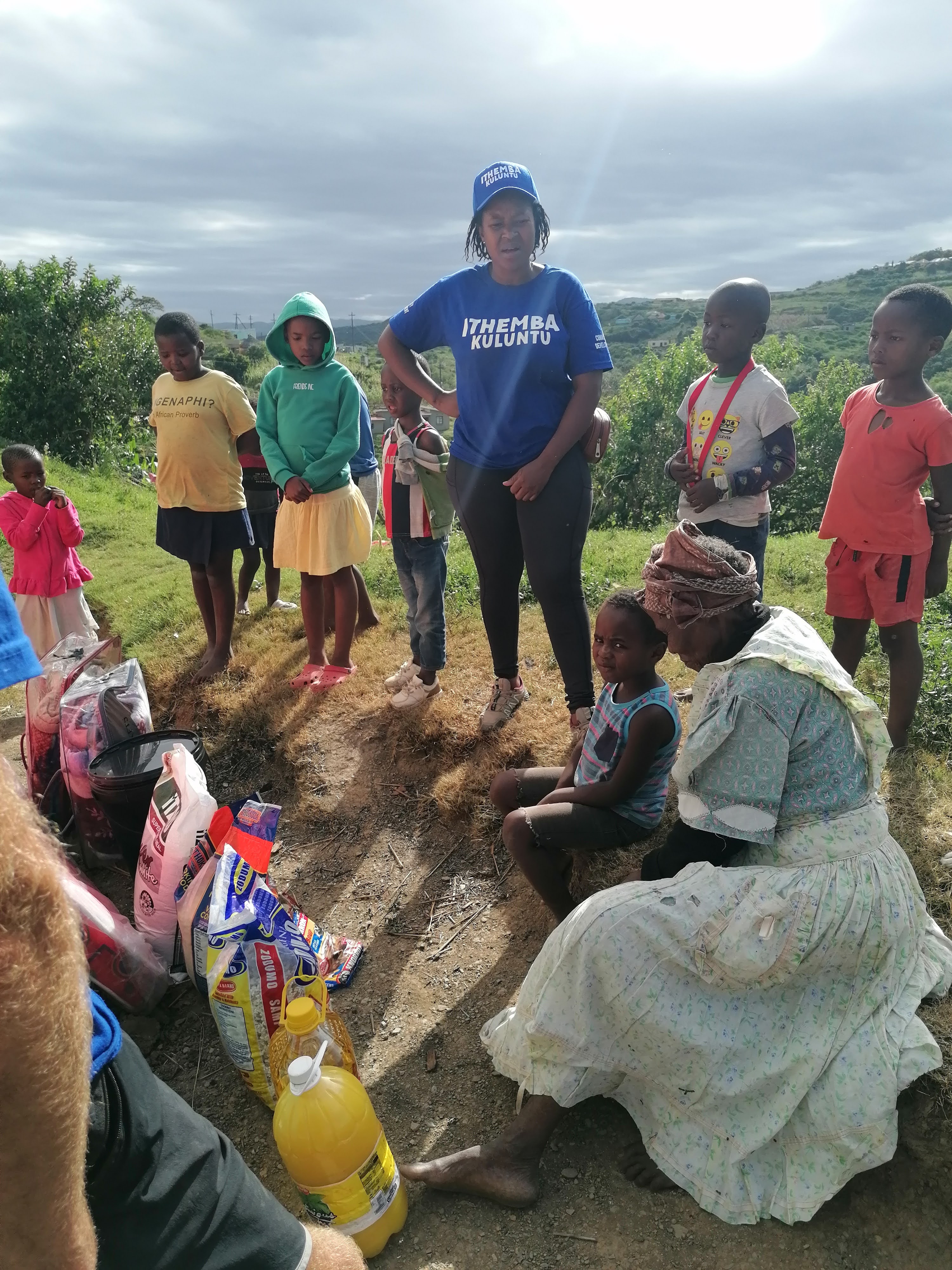 Community worker supporting an older woman with relief supplies