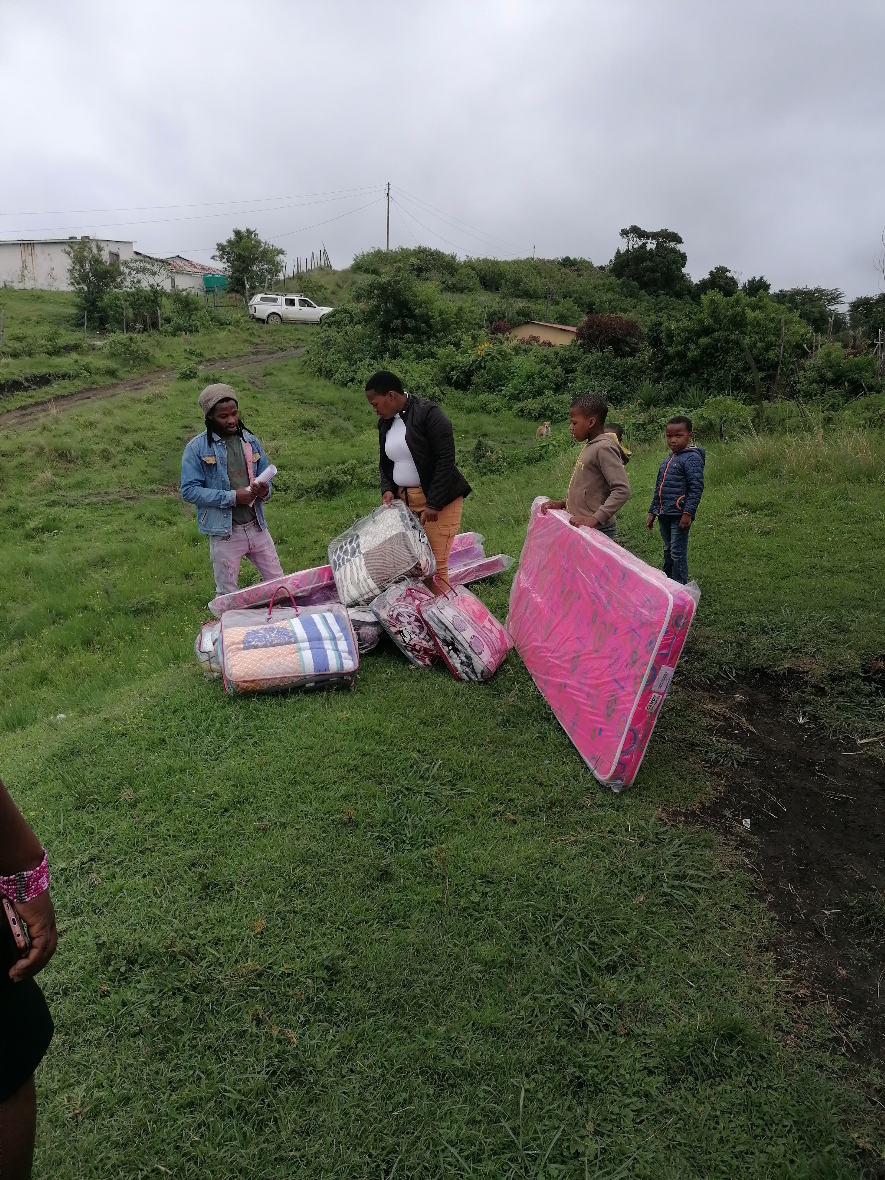 Relief team carrying mattresses across a rural field