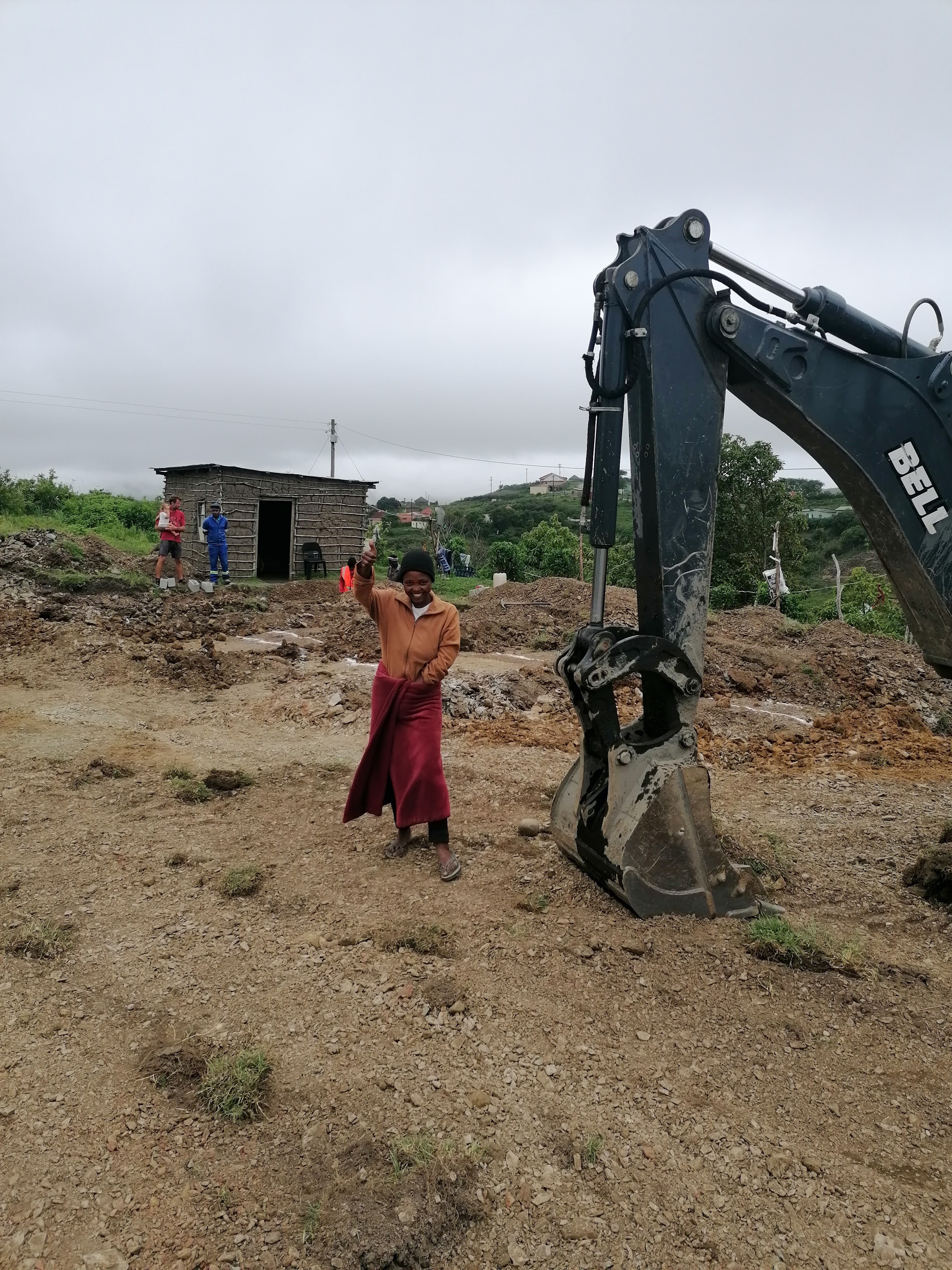 Woman beside an excavator clearing a damaged property