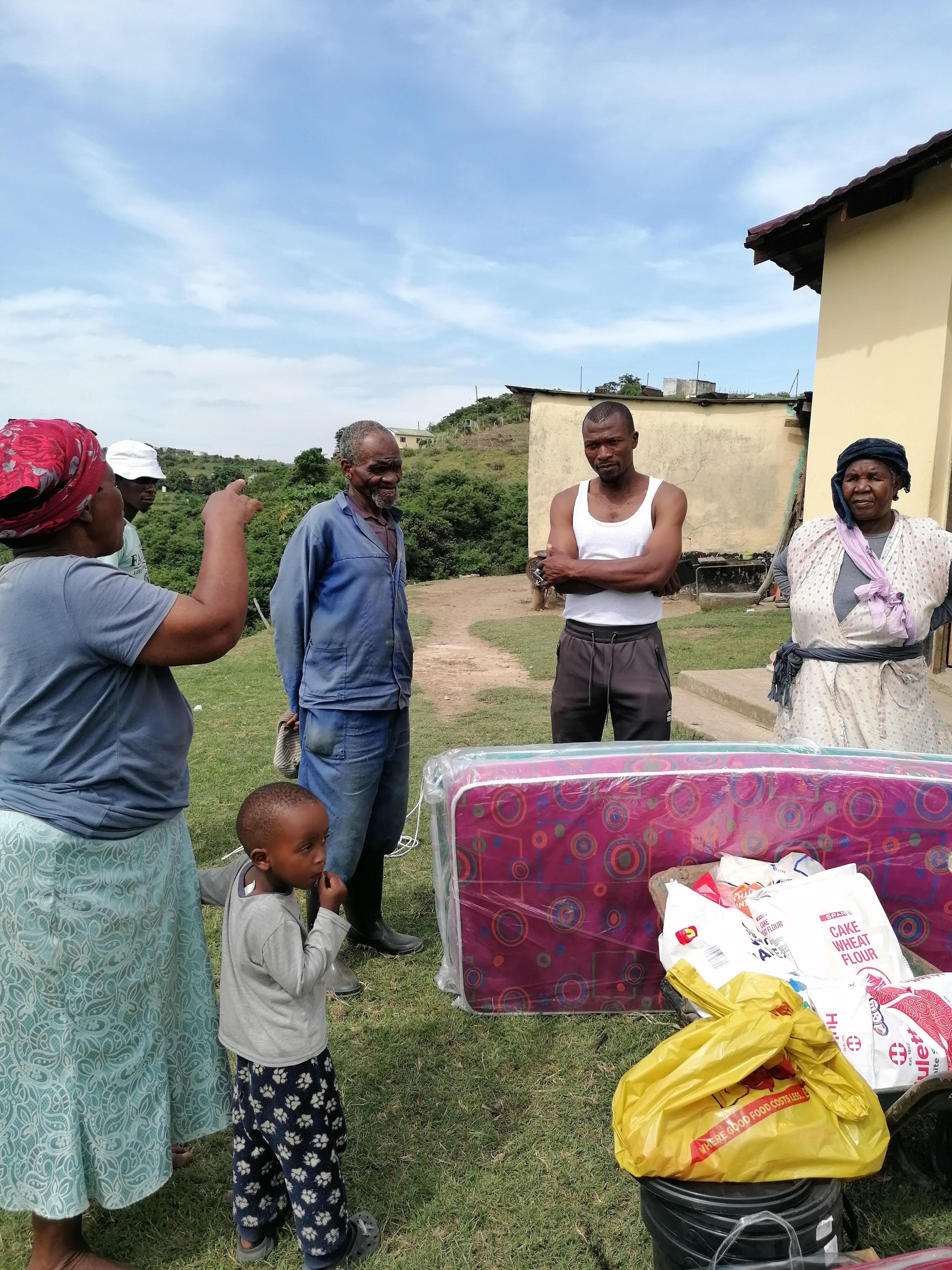 Community members with a mattress and household relief supplies