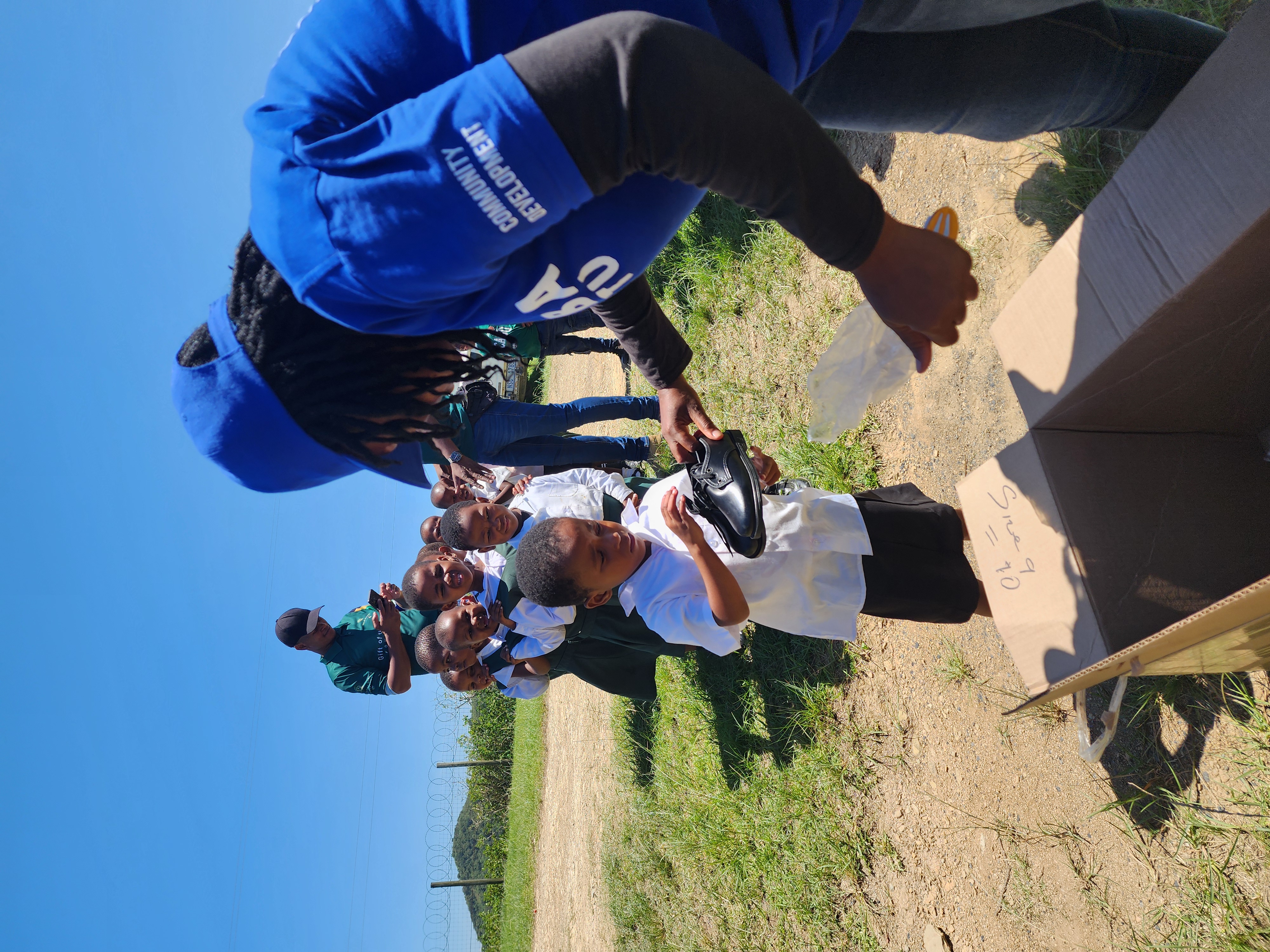 Community worker fitting children with new school shoes