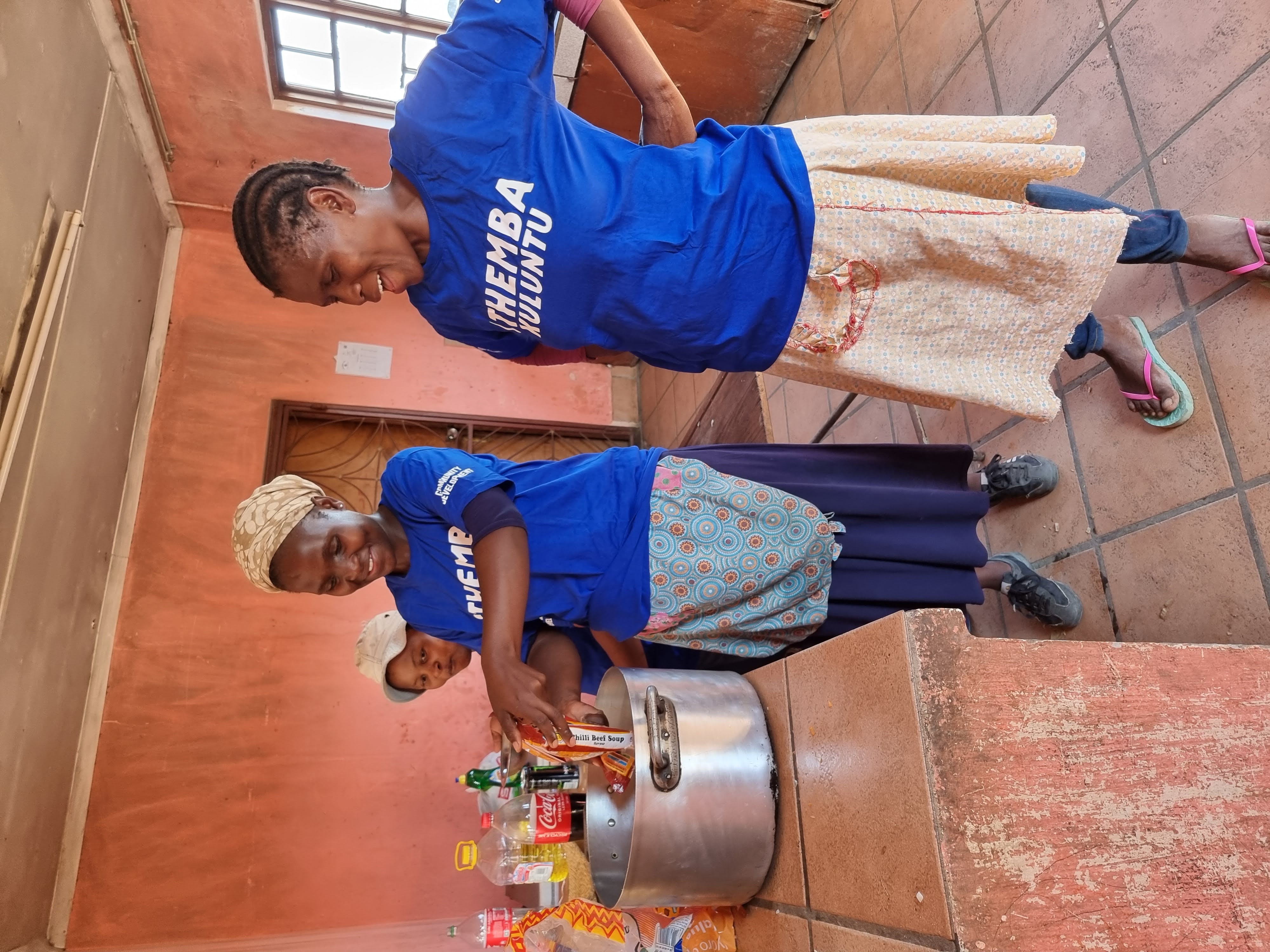 Women cooking in a large pot for the community