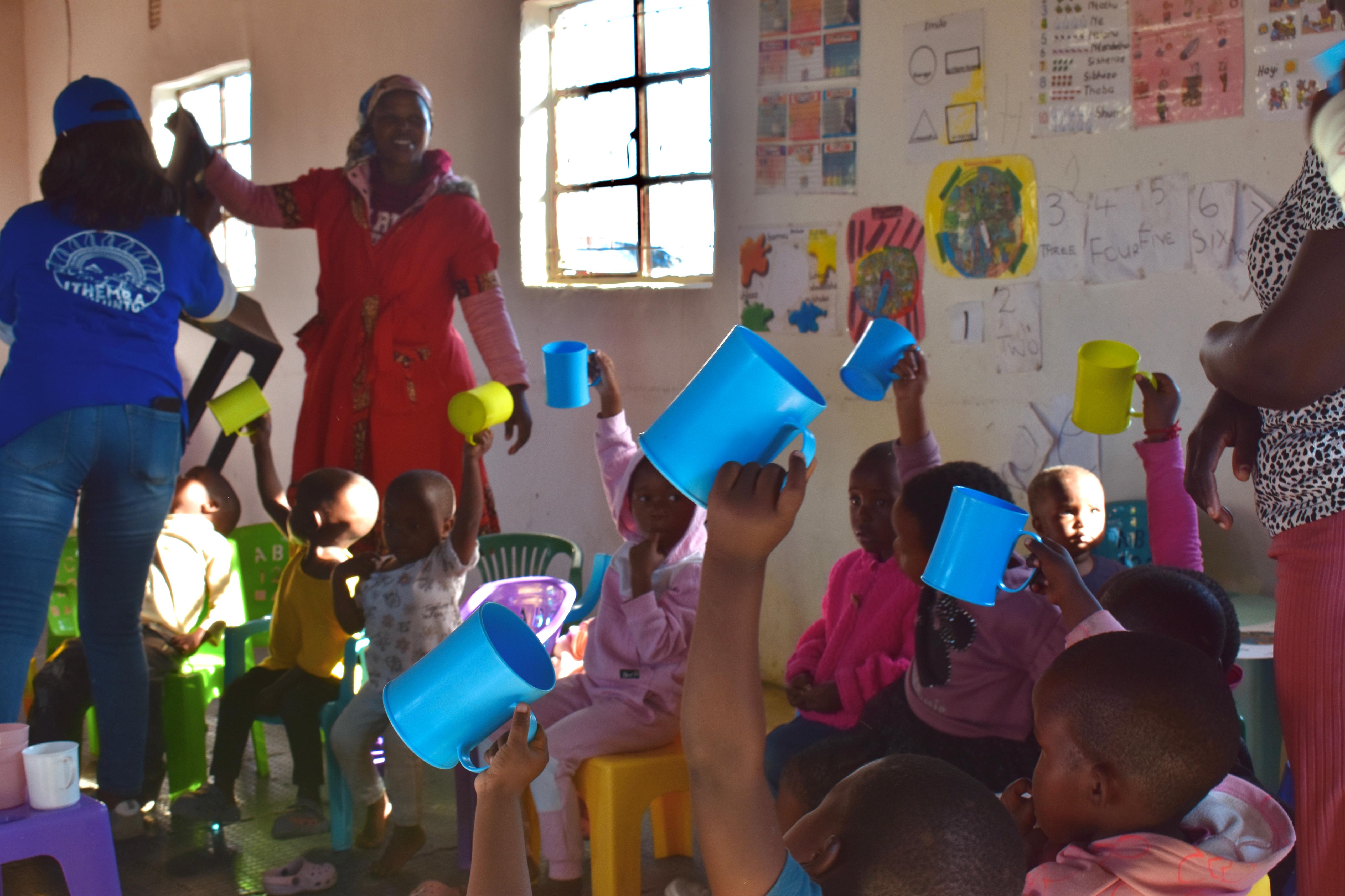 Children holding drinking cups during rural ECD safe-water education