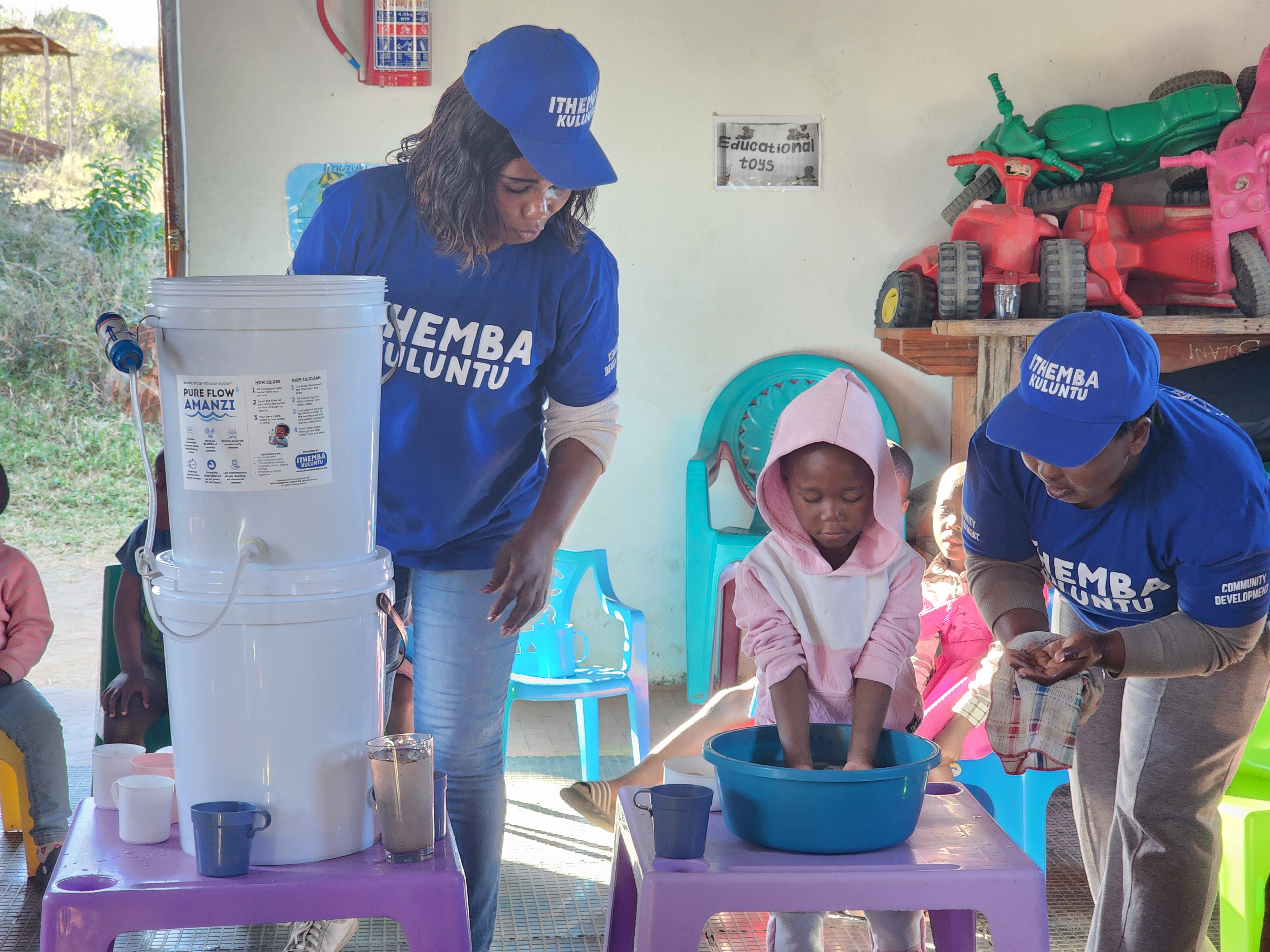 Teachers guiding a child through handwashing at a rural ECD centre